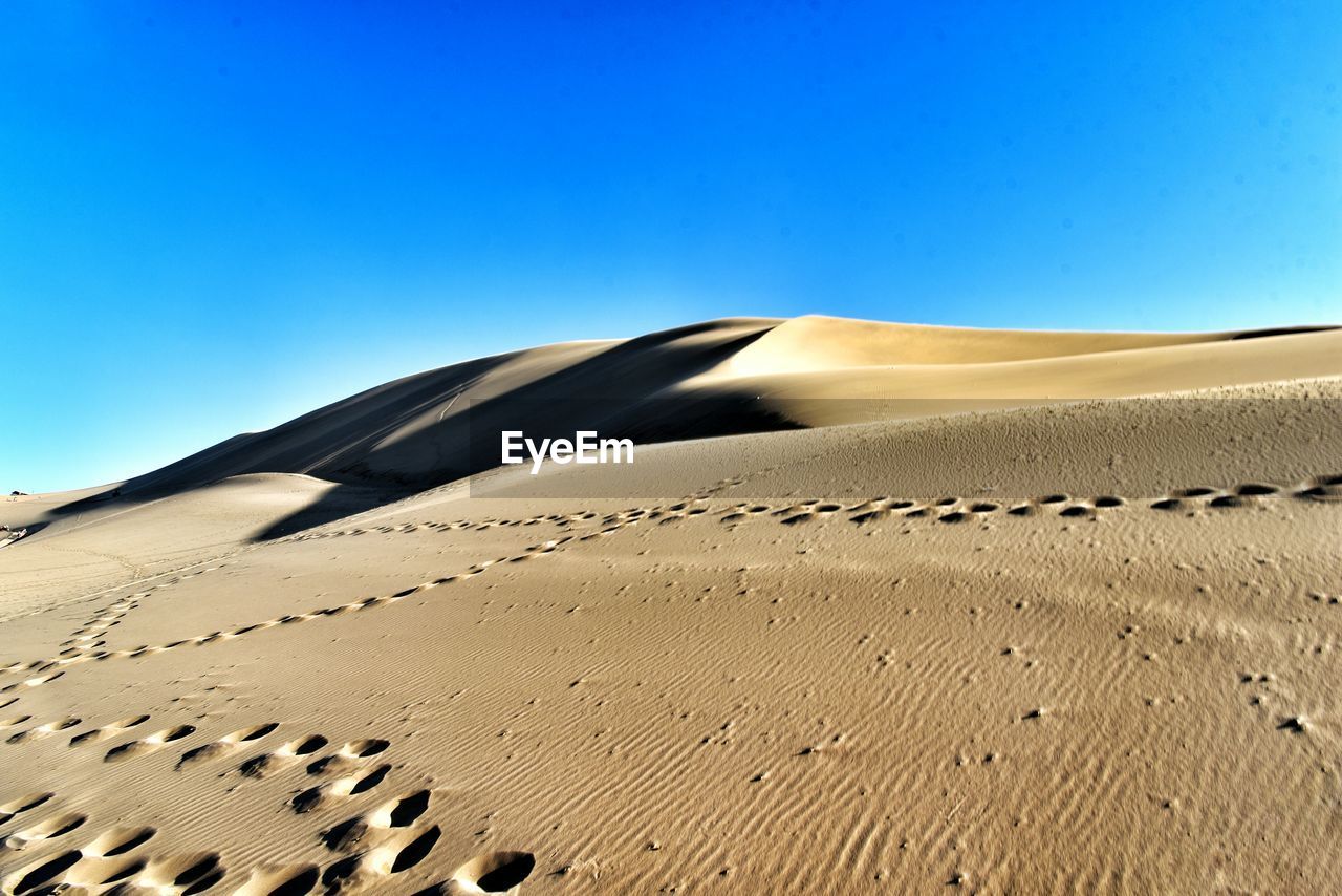 Scenic view of desert against clear blue sky