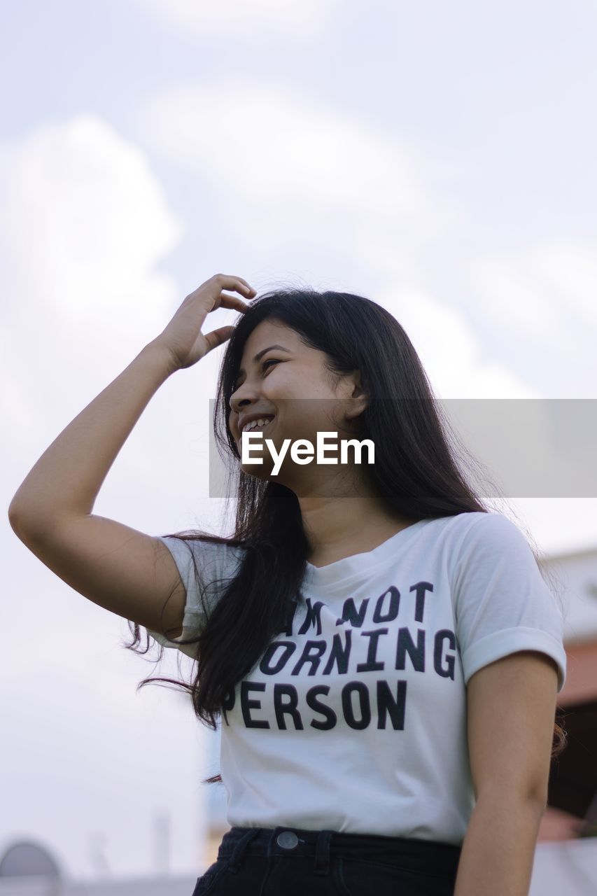 Portrait of a smiling young woman against sky