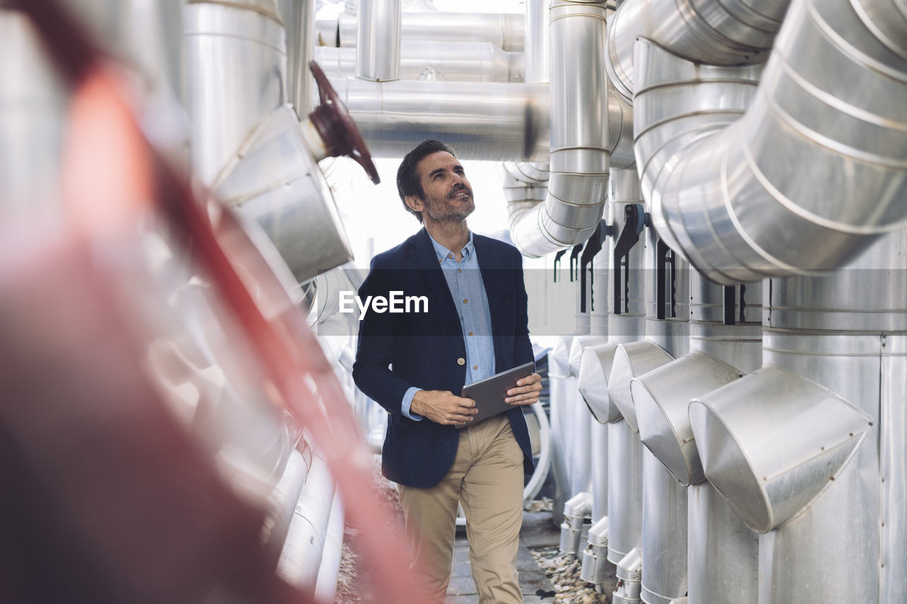 Smiling businessman looking at machinery in factory