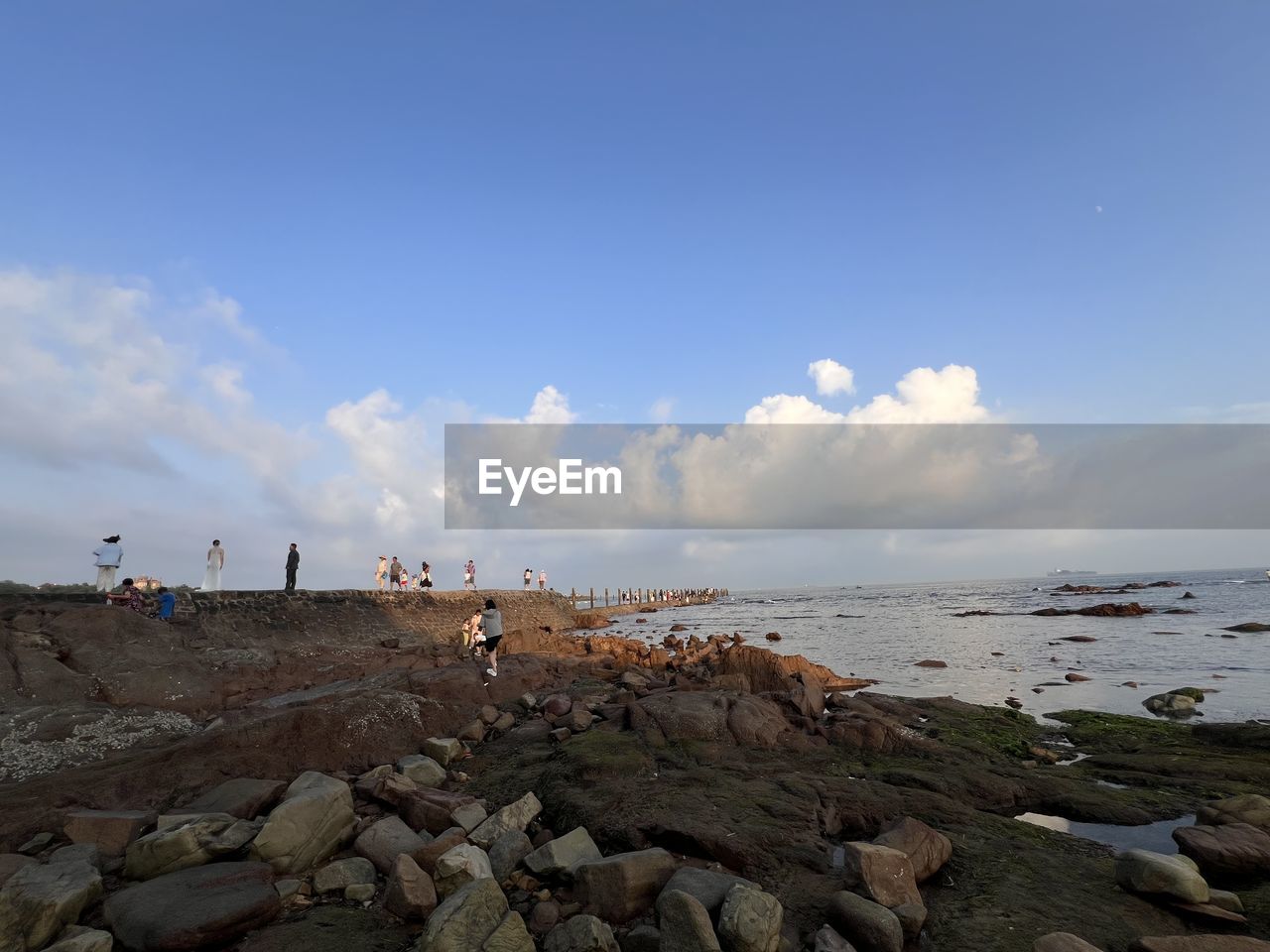 shore, sky, sea, water, coast, body of water, beach, horizon, ocean, land, rock, nature, group of people, cloud, wave, holiday, beauty in nature, trip, vacation, scenics - nature, travel, sand, bay, large group of people, travel destinations, environment, blue, leisure activity, tourism, tourist, horizon over water, day, outdoors, men, crowd, coastline, tranquility, lifestyles, adult, landscape, summer, tranquil scene