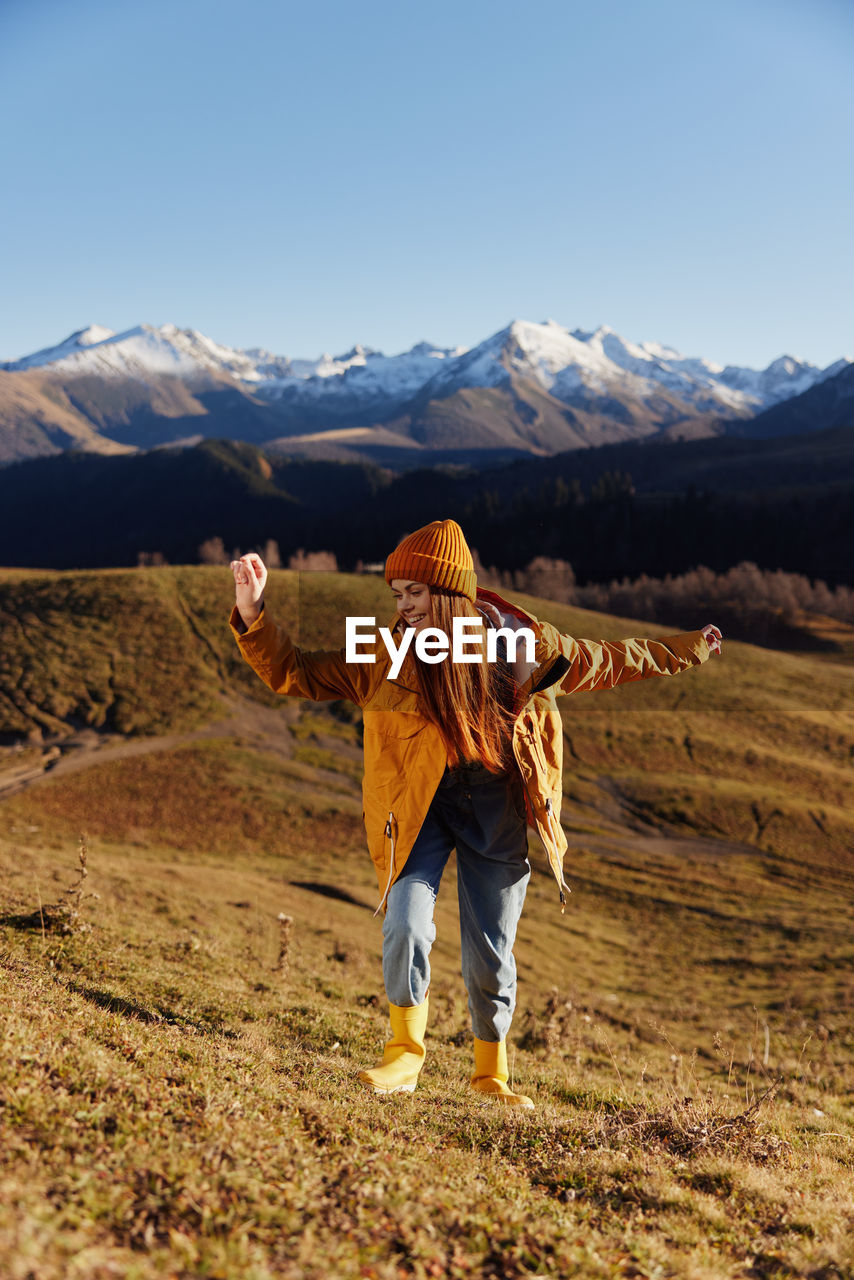 rear view of woman standing on mountain against sky