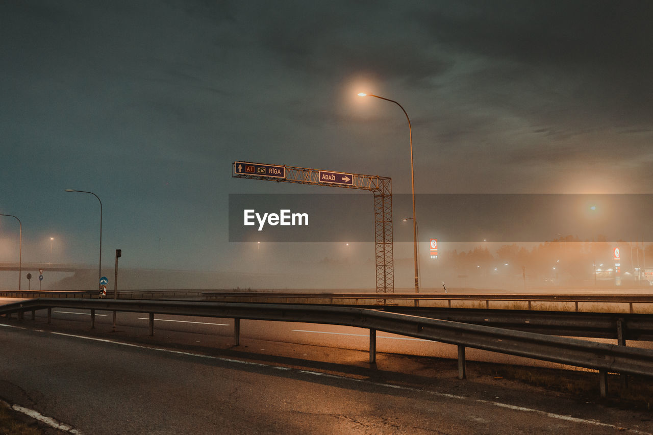 ILLUMINATED STREET LIGHTS AGAINST SKY AT NIGHT