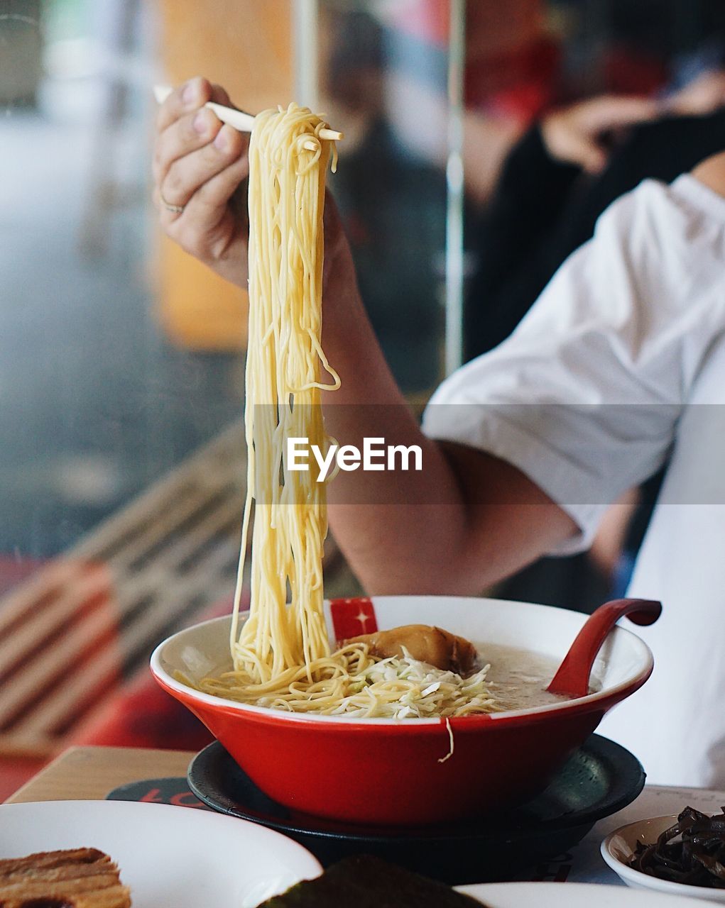Cropped image of woman having spaghetti at table