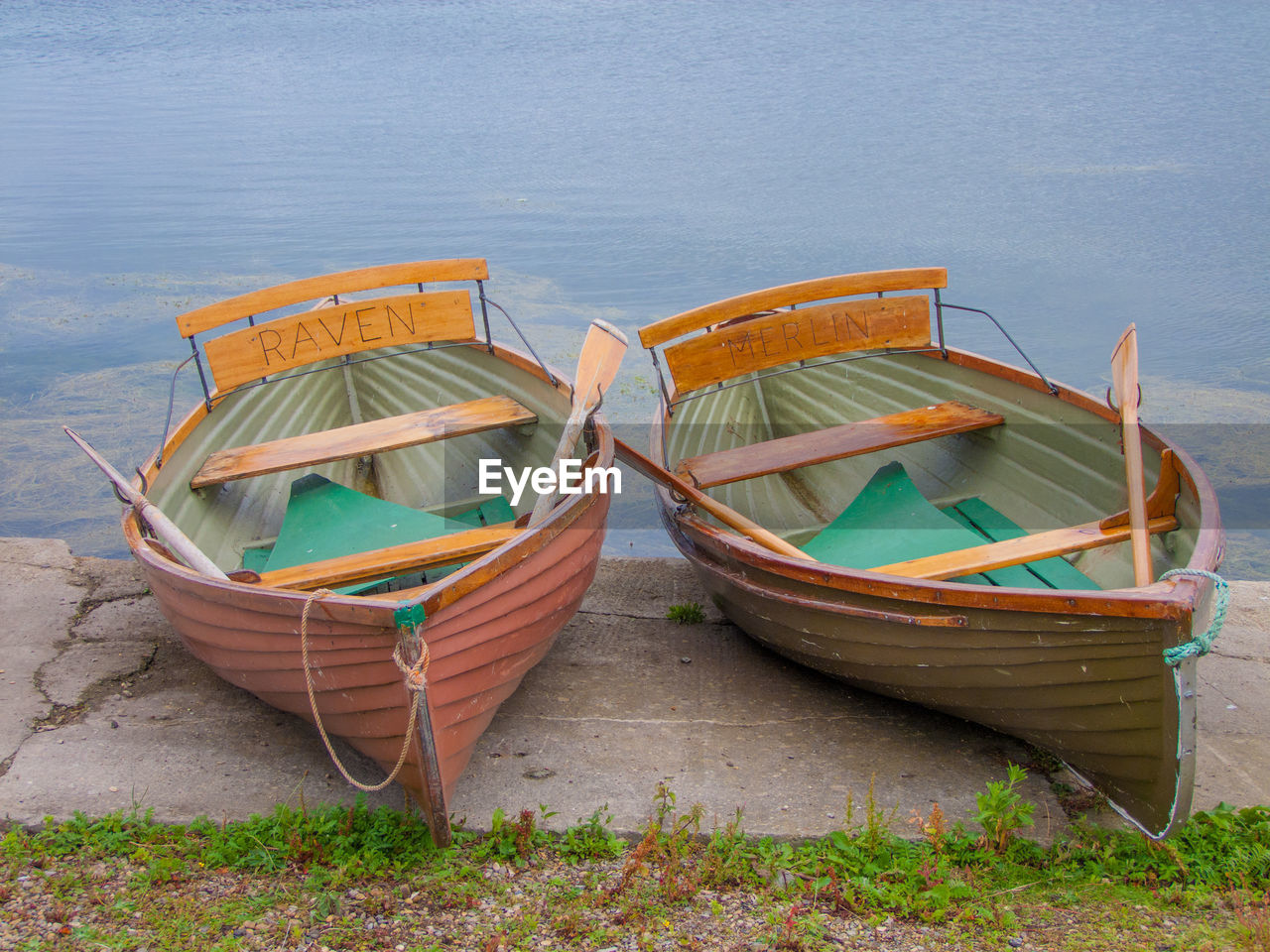 Text on boats moored at lakeshore by field