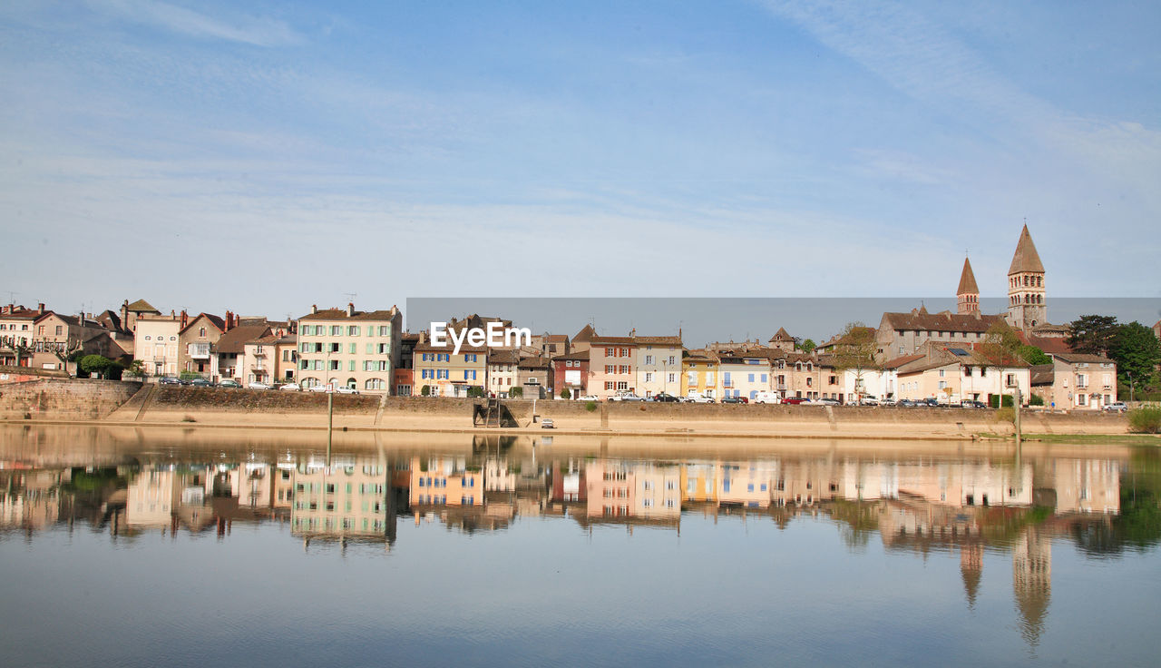 Reflection of buildings in lake against sky in city