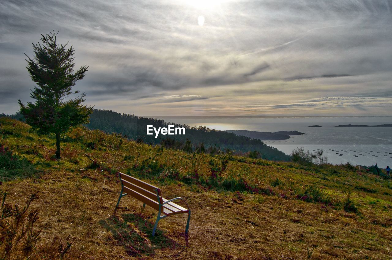 View of calm beach against cloudy sky