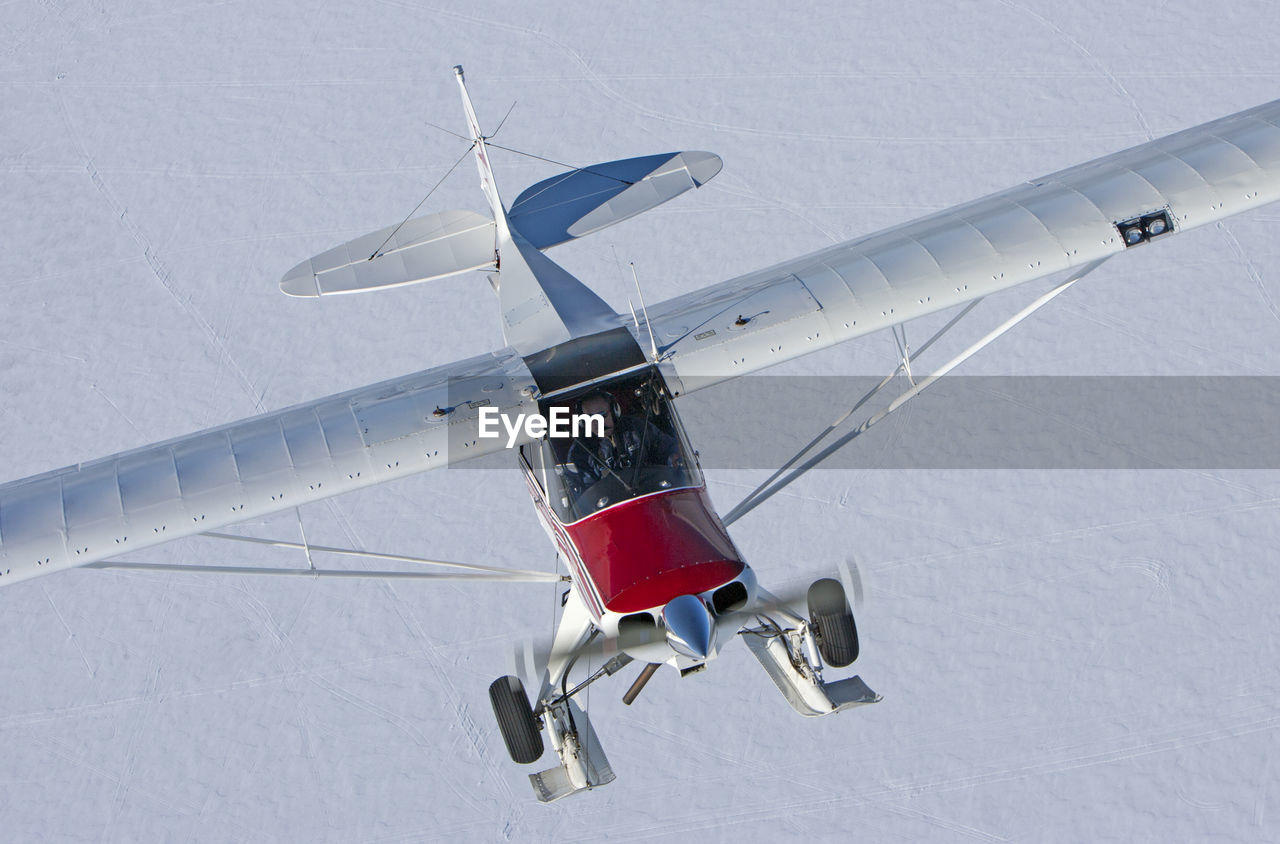 High angle view of airplane flying over snow covered land