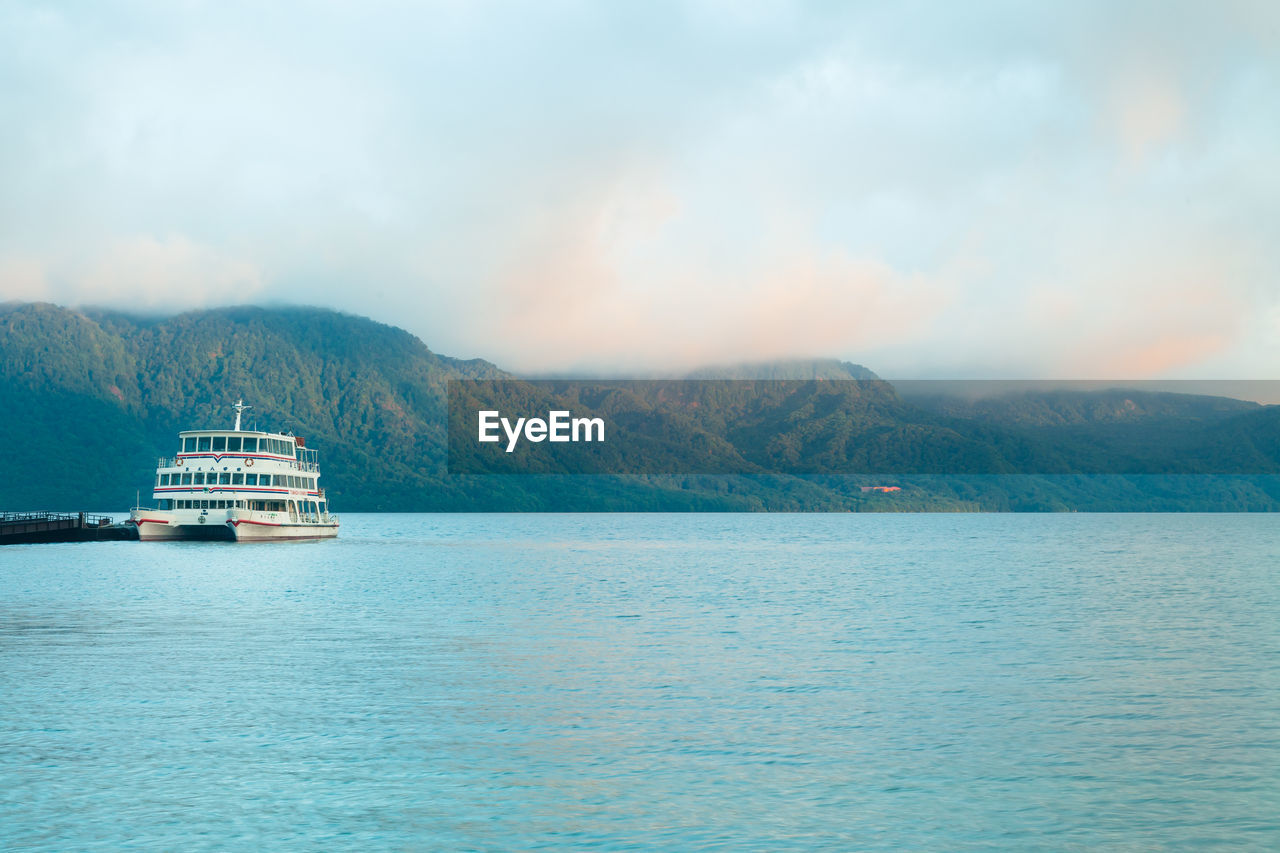 Tourist boat docked in lake towada, japan. early morning scene by the lake.