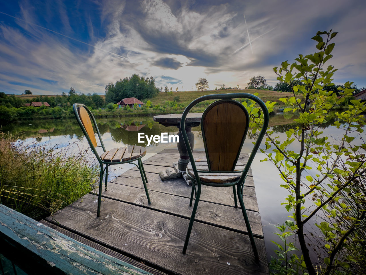 sky, nature, water, cloud, plant, reflection, chair, seat, tranquility, sunlight, beauty in nature, no people, tree, scenics - nature, landscape, environment, morning, relaxation, summer, grass, land, travel destinations, tranquil scene, outdoors, architecture, lake, dusk, trip, vacation, wood, travel, holiday, table, absence, food and drink, beach, idyllic, outdoor chair, blue