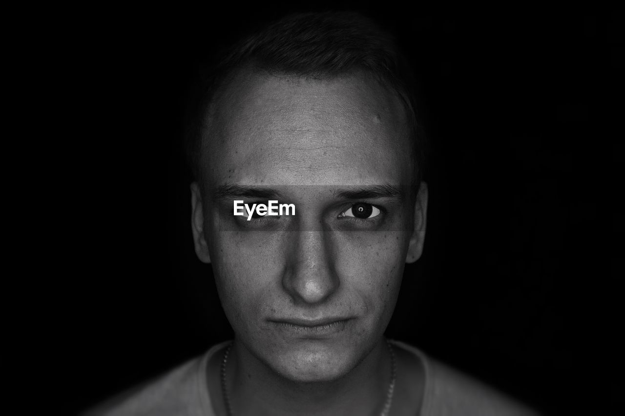 Close-up portrait of young man against black background