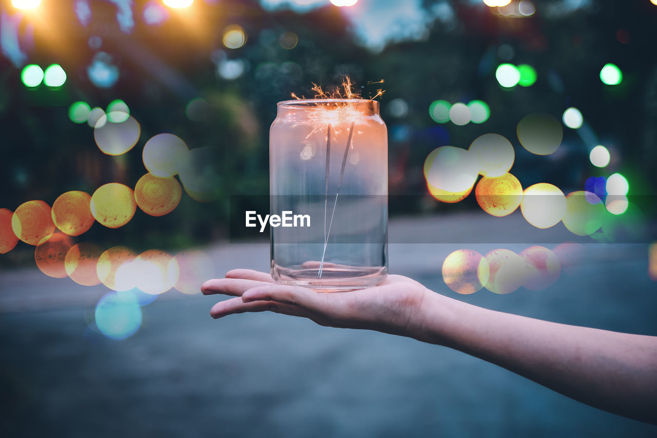 Close-up of hand holding jar with burning sparklers