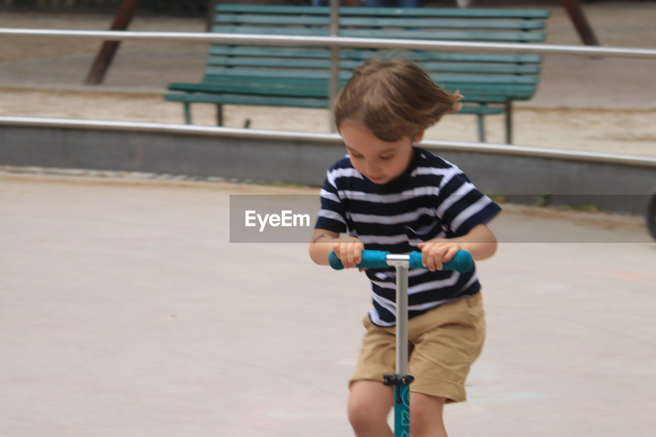 Boy riding push scooter on road