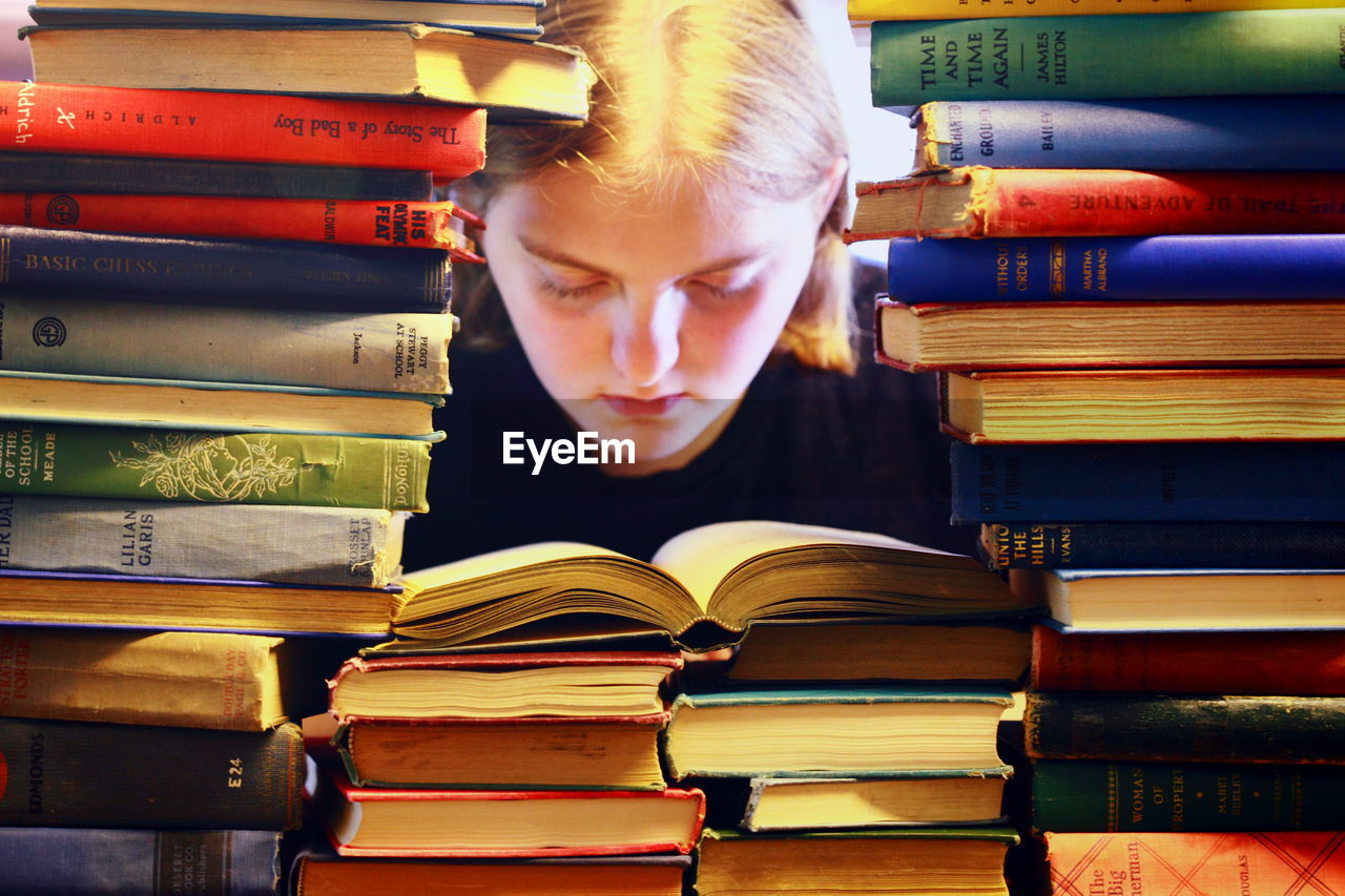 Teenage girl reading book in library