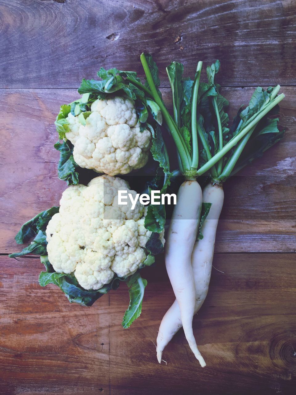 High angle view of cauliflowers and radishes on wooden table