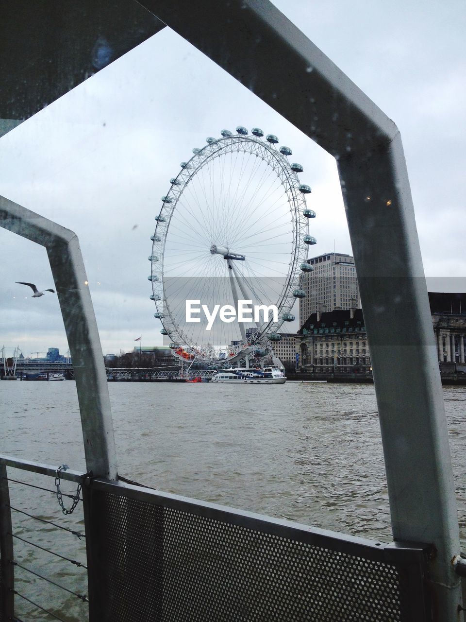 Millennium wheel by thames river against sky