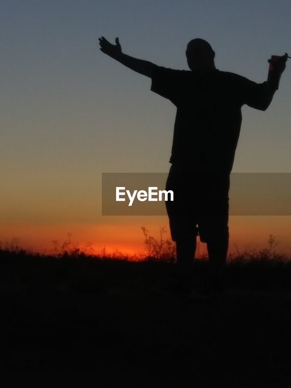 SILHOUETTE MAN STANDING ON FIELD DURING SUNSET