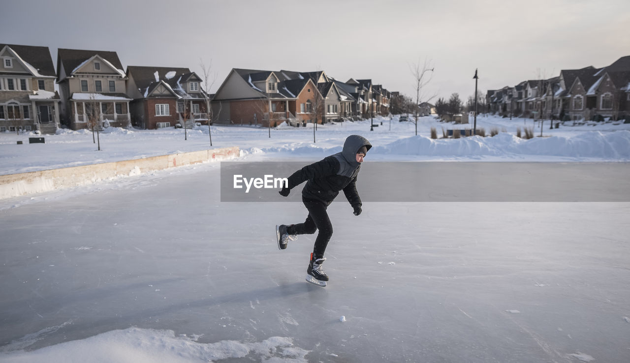 Teenage boy skating on an outdoor neighbourhood ice rink.