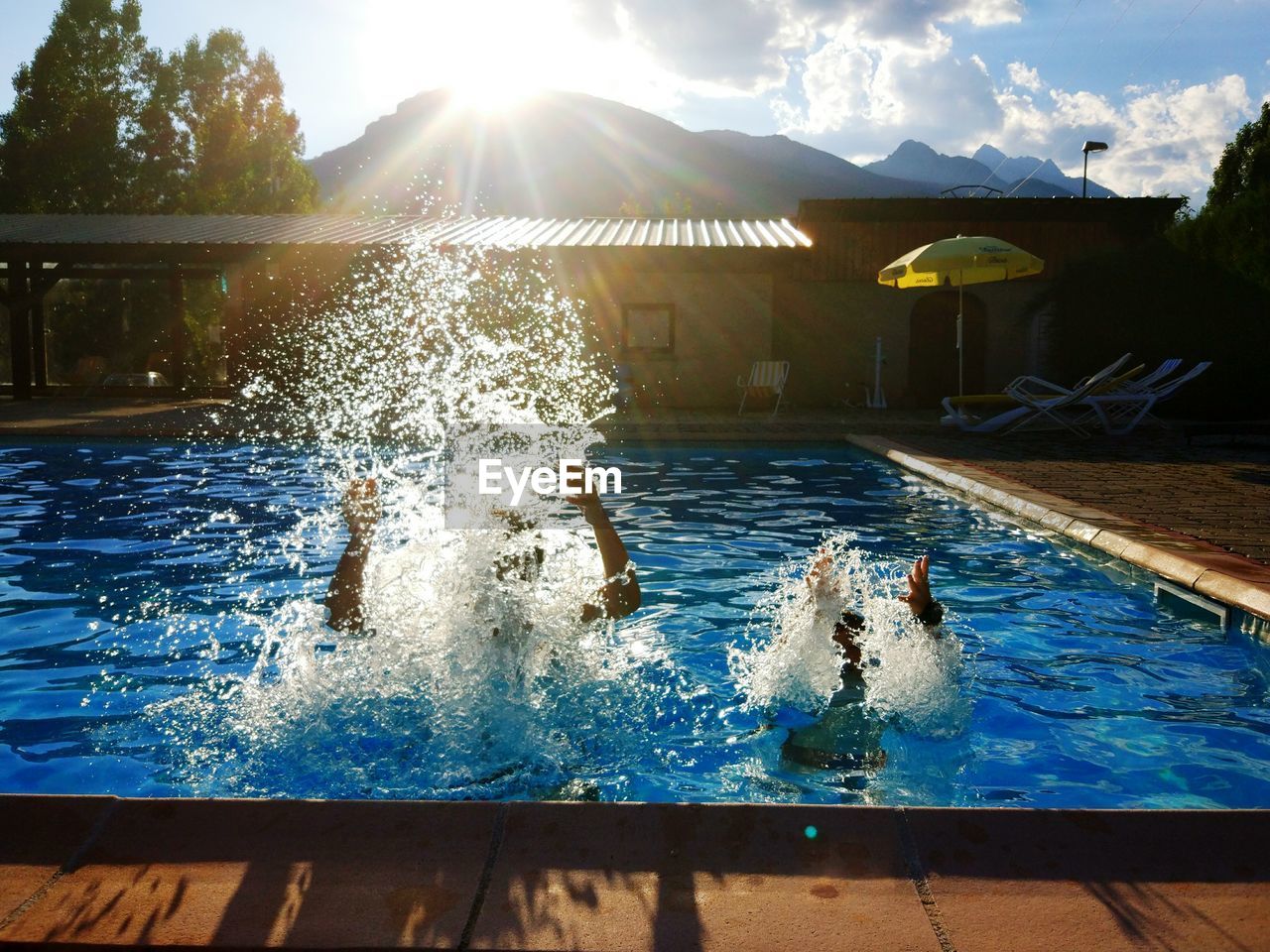 People splashing water in swimming pool against sky