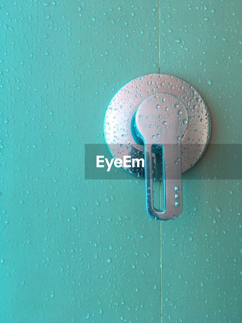 CLOSE-UP OF METAL DOOR WITH WATER DROPS ON BLUE BACKGROUND