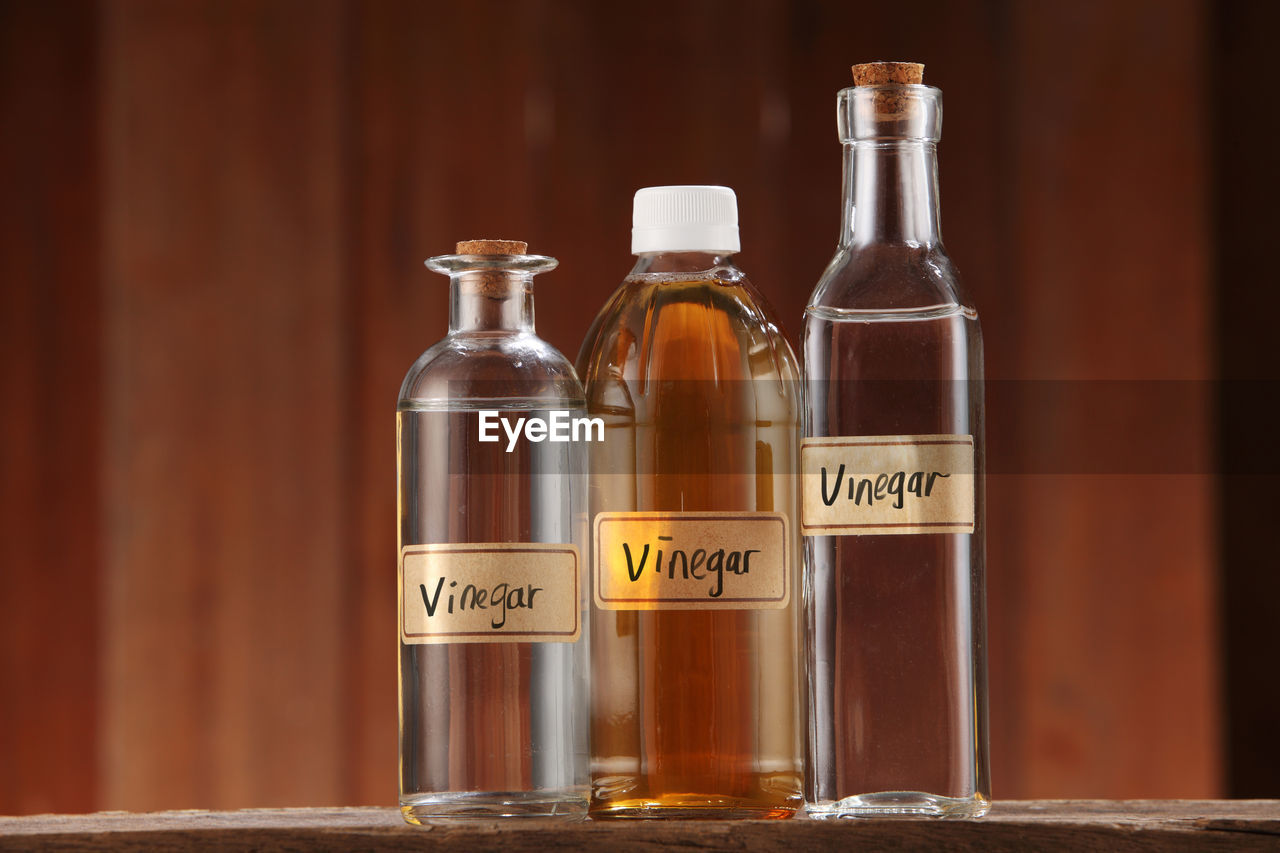 Apple cider vinegar and white vinegar on wooden background