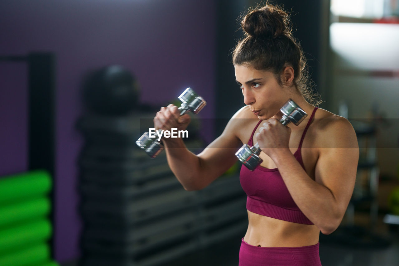 Young woman in drinking glass while standing against blurred background