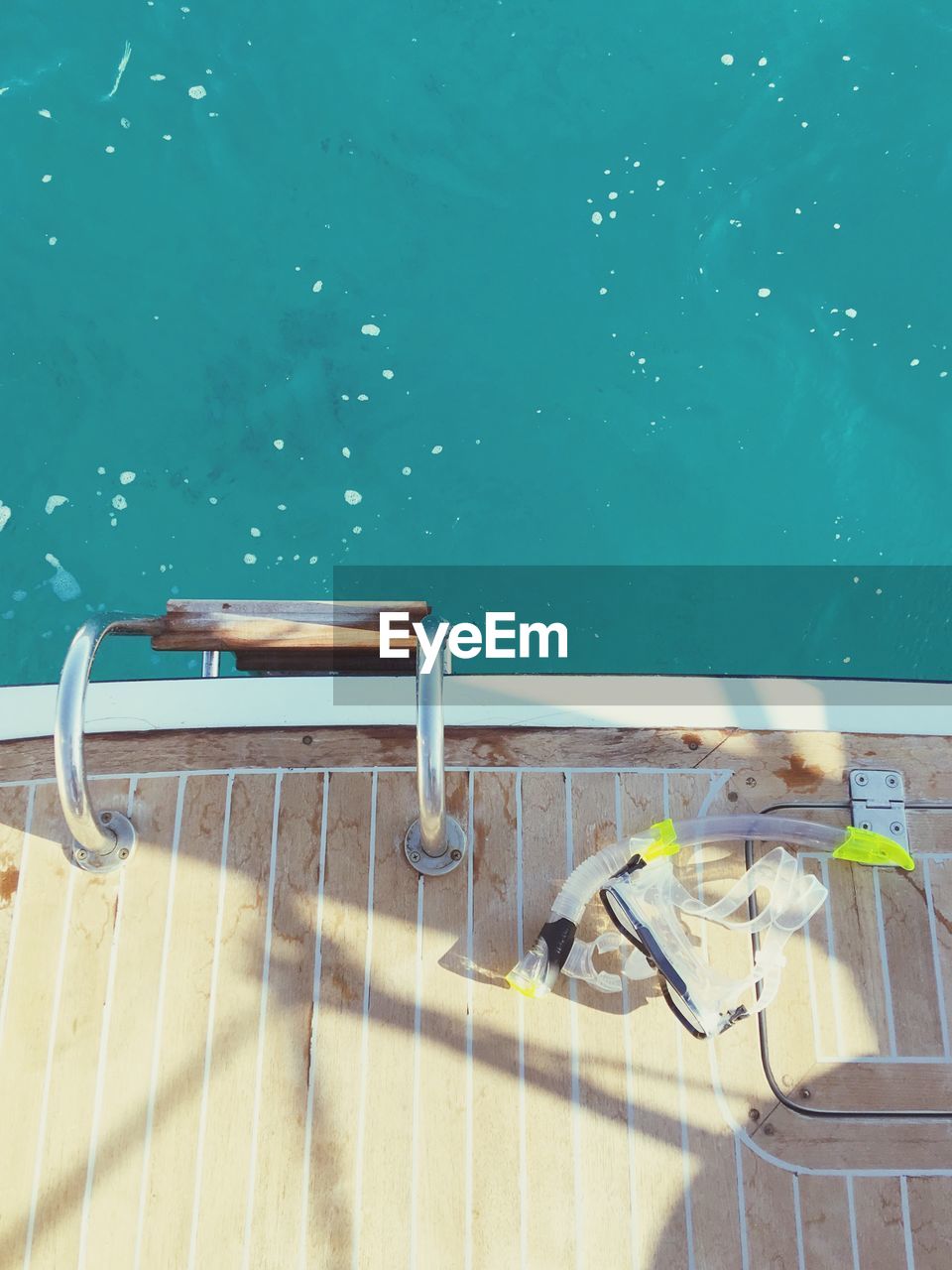 High angle view of snorkel and swimming goggles on boat deck in sea