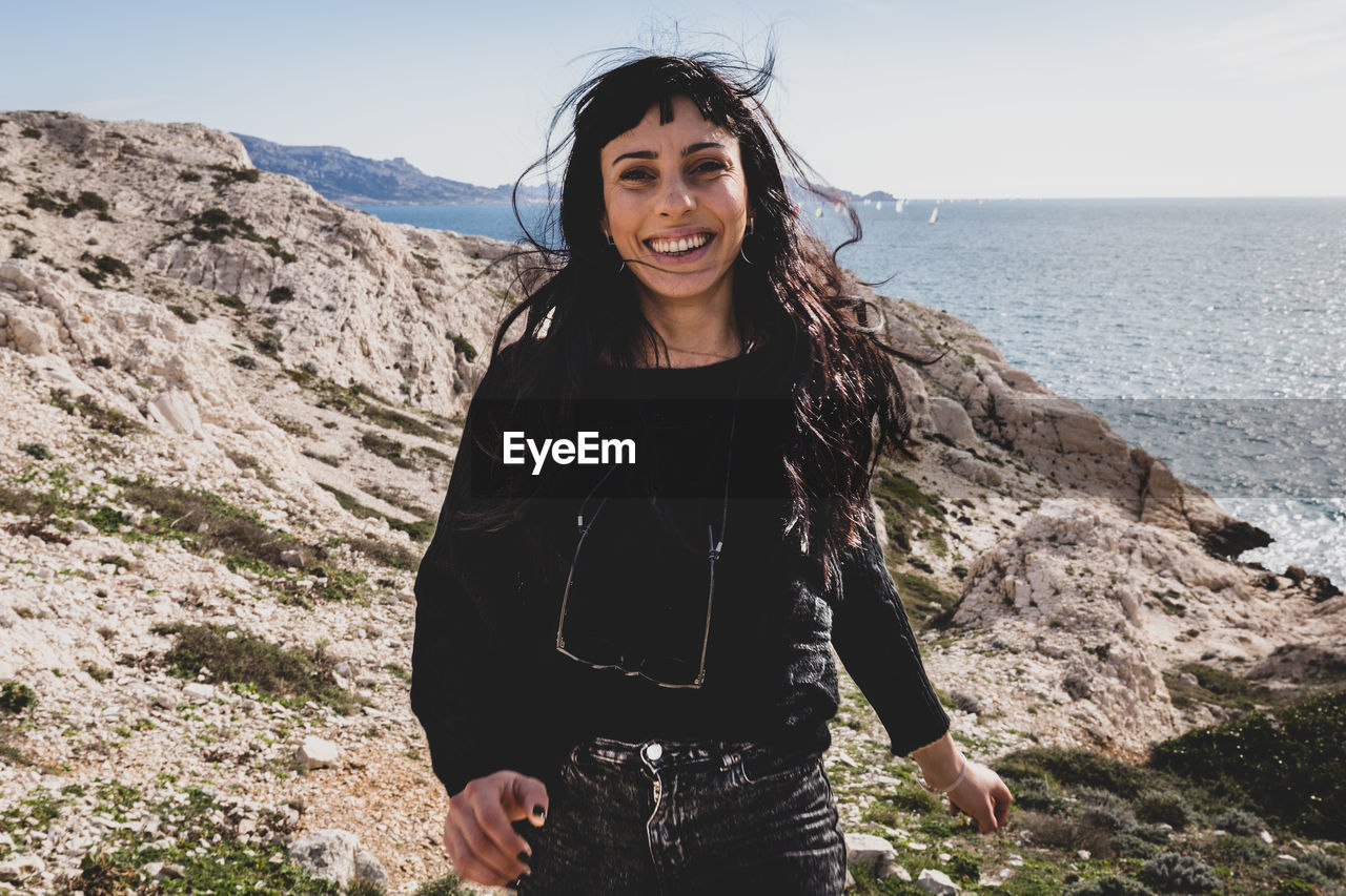 Portrait of happy woman standing at beach