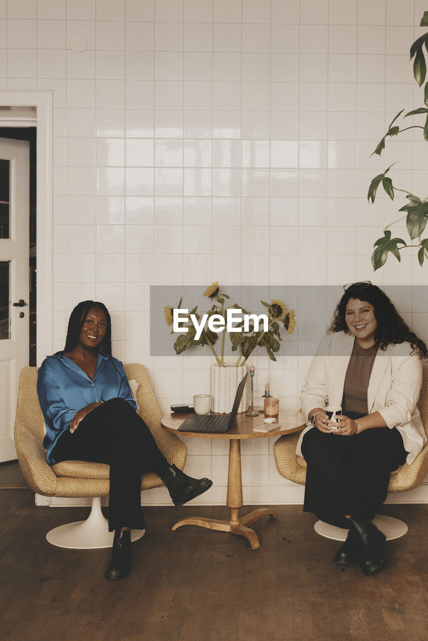 Portrait of smiling businesswomen sitting together on chairs at office