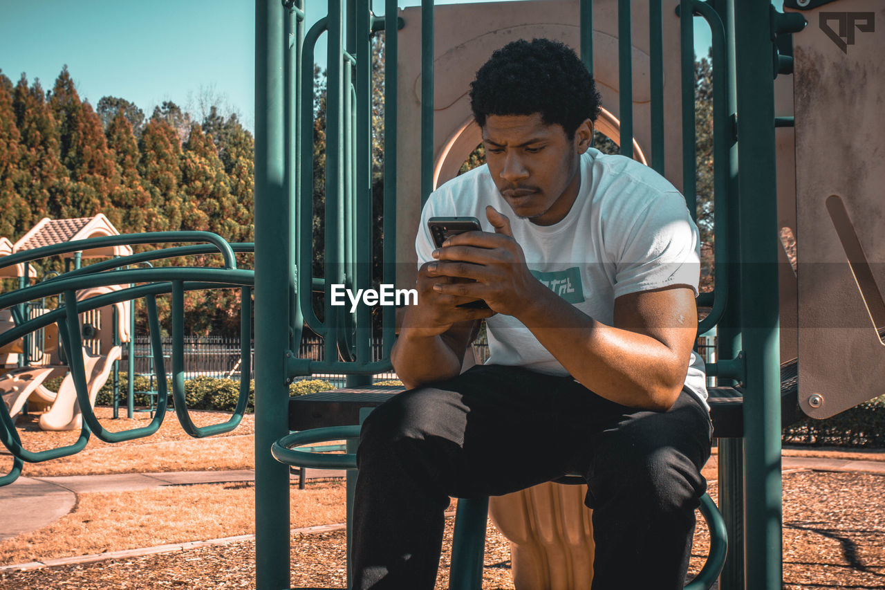 Young man using mobile phone while sitting on seat