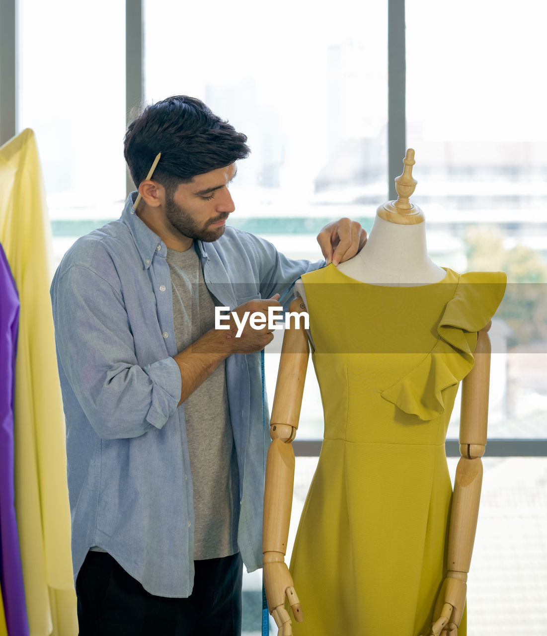 Male fashion designer taking measurements at boutique