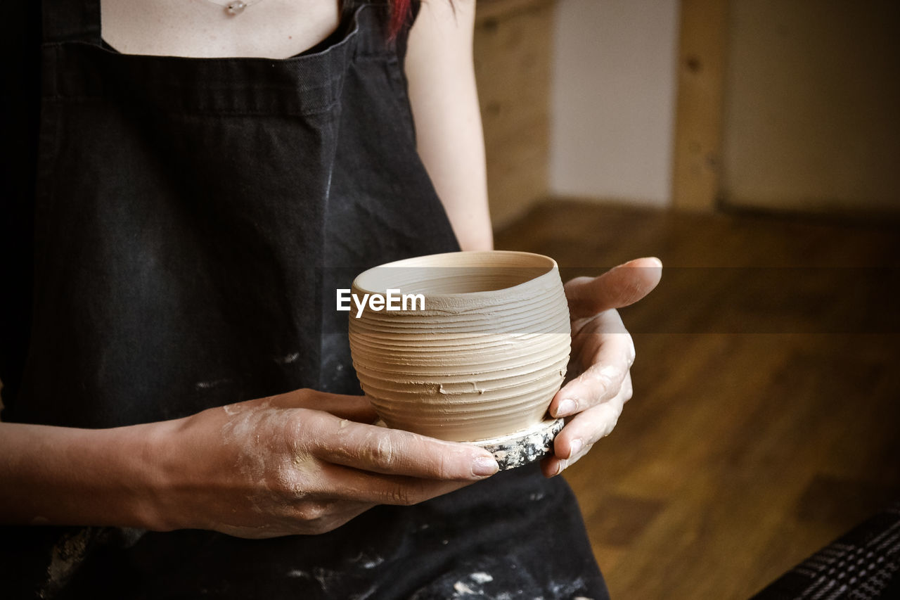 A raw clay pot in the hands of a potter. master crock.