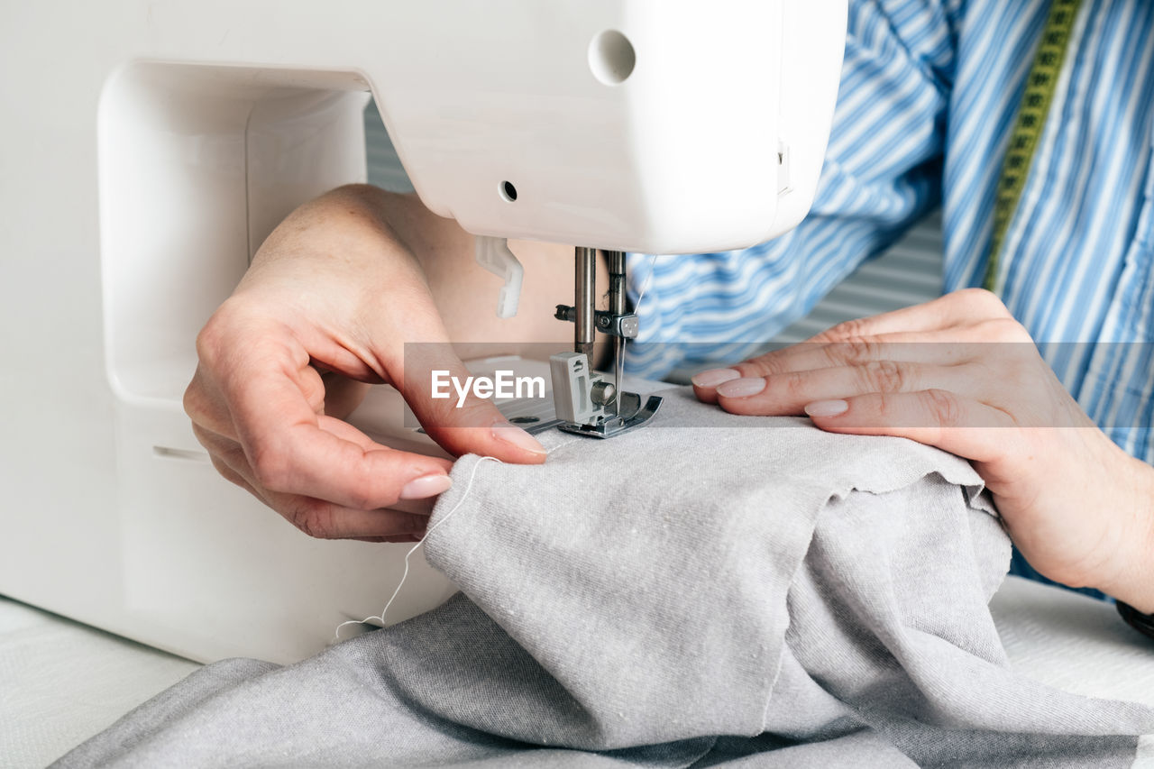 Midsection of craftswoman sewing textile on machine at workshop