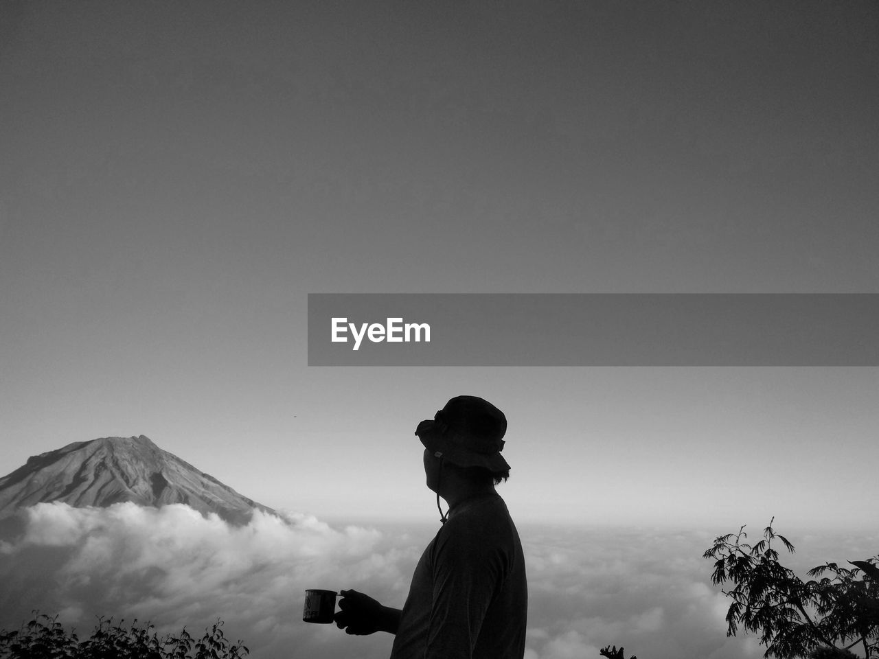 A man standing on a mountain enjoying coffee with a beautiful sea of clouds and clear sky.