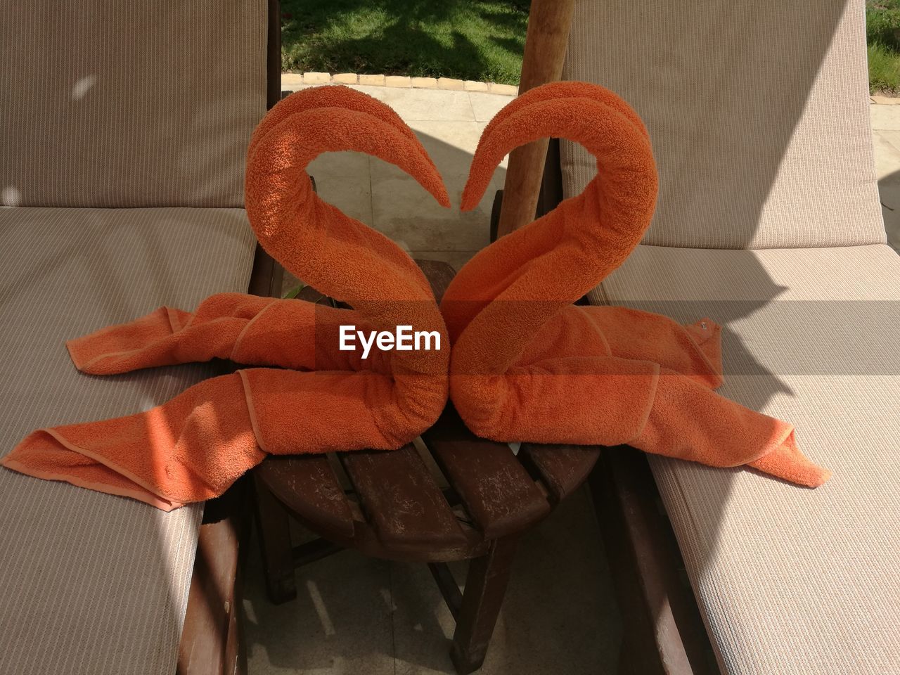 High angle view of orange heart shape towels on table amidst lounge chairs