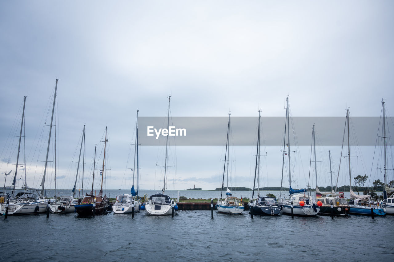 nautical vessel, water, transportation, mode of transportation, sailboat, marina, sea, sky, harbor, pole, mast, dock, moored, ship, boat, nature, vehicle, cloud, no people, travel, sailing, beauty in nature, day, yacht, tranquility, watercraft, outdoors, travel destinations, holiday, in a row, bay, port, vacation, idyllic, tranquil scene, trip, sailing ship, scenics - nature, environment, pier