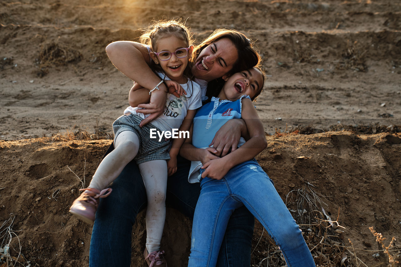 A mother sitting on the field plays with her daughters