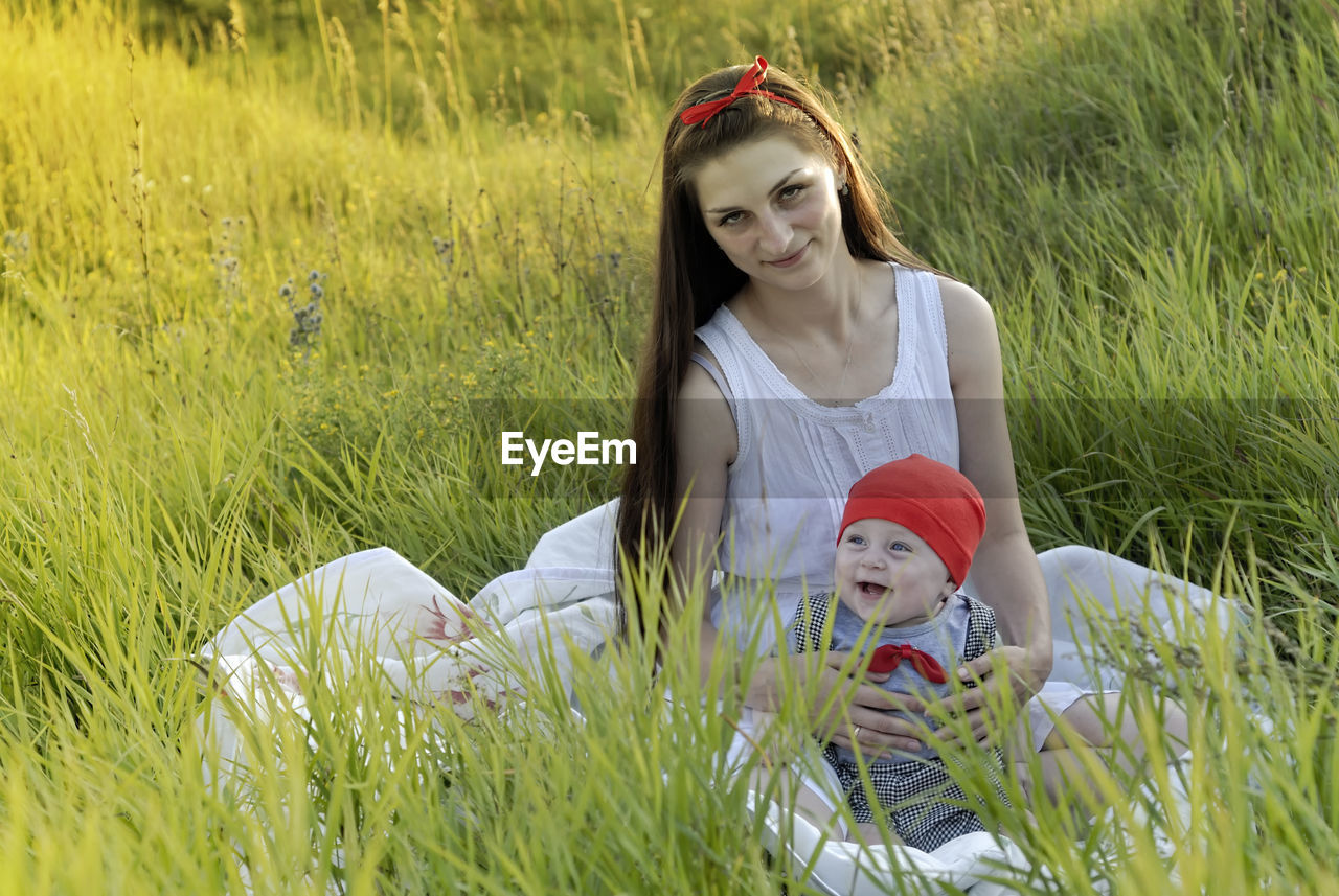 PORTRAIT OF SMILING GIRL SITTING ON GRASS FIELD