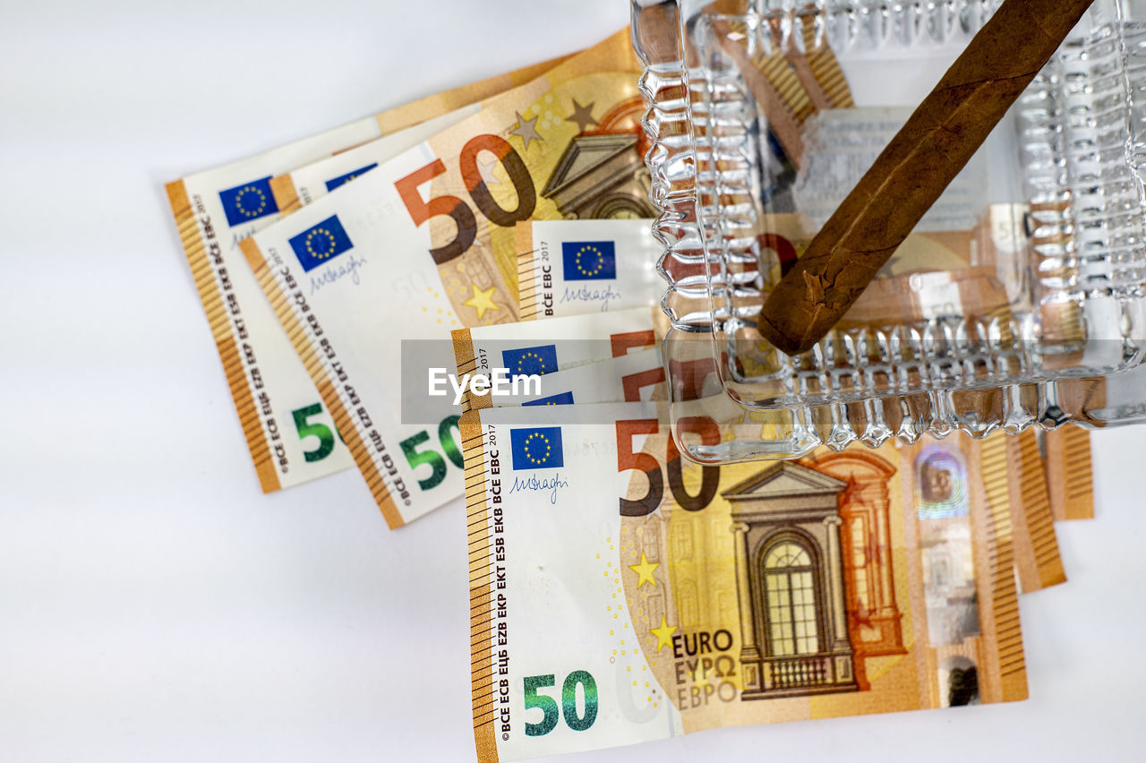 Close-up of cigar in ash tray over banknotes