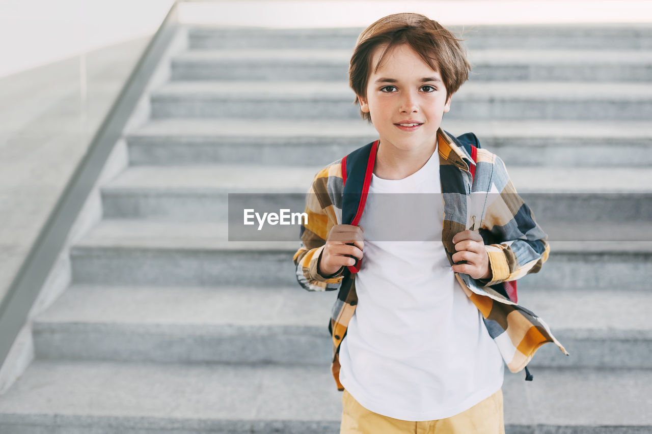 Portrait of boy holding umbrella on staircase