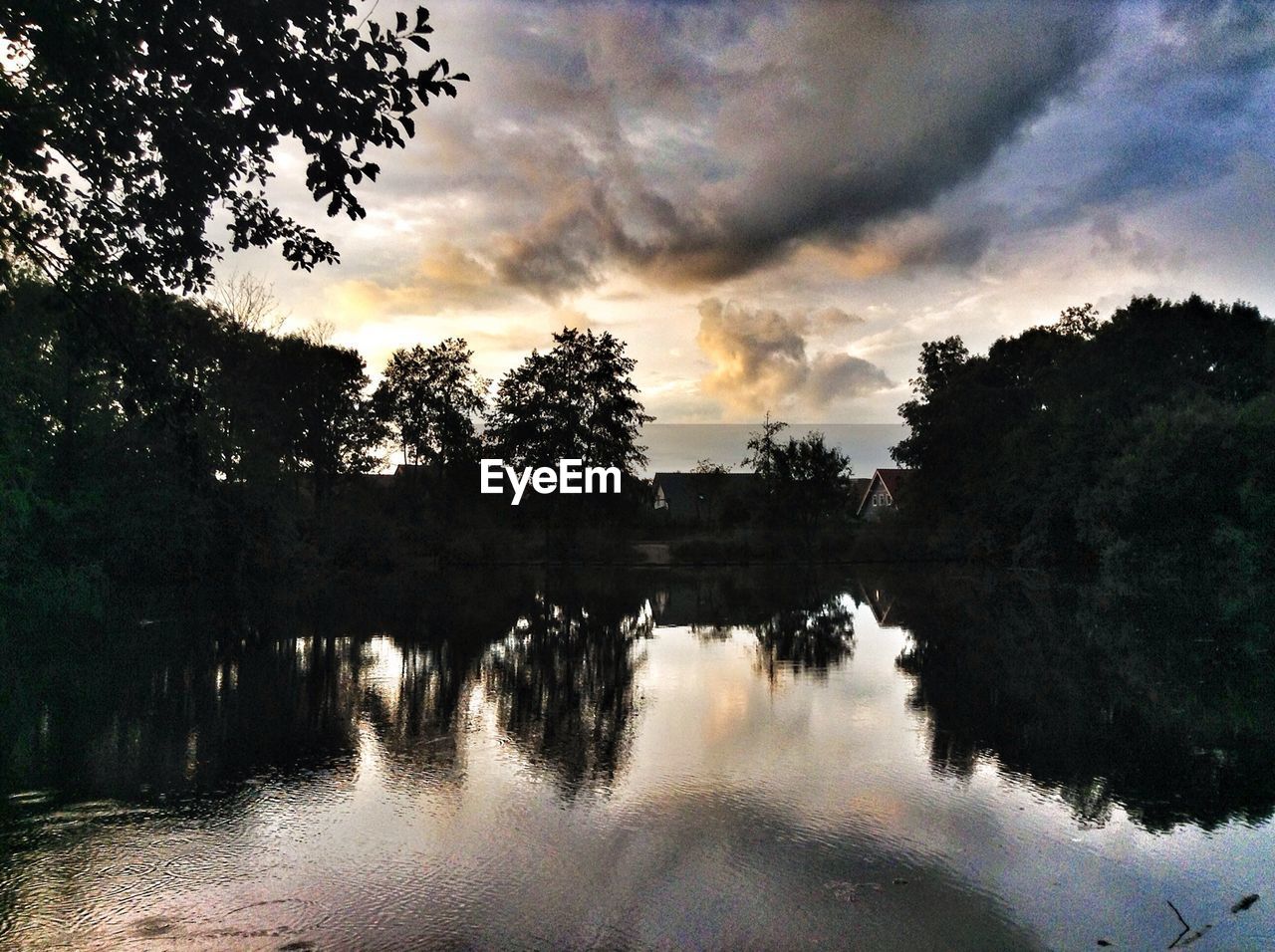 SCENIC VIEW OF LAKE AGAINST CLOUDY SKY AT SUNSET