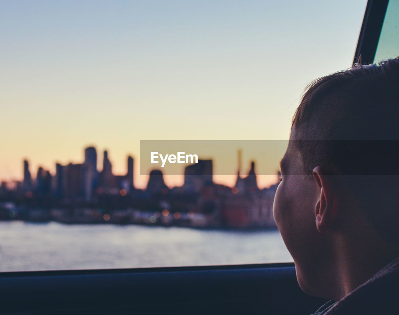 Close-up of man in city against sky during sunset