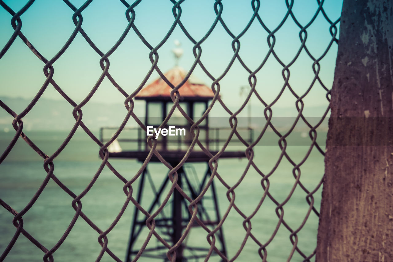 Close-up of chainlink fence against sea