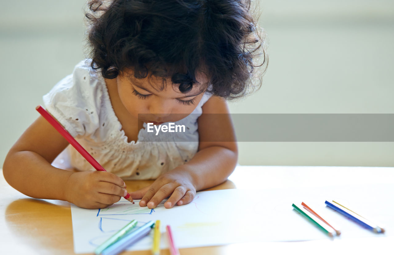 High angle view of girl drawing on book at table