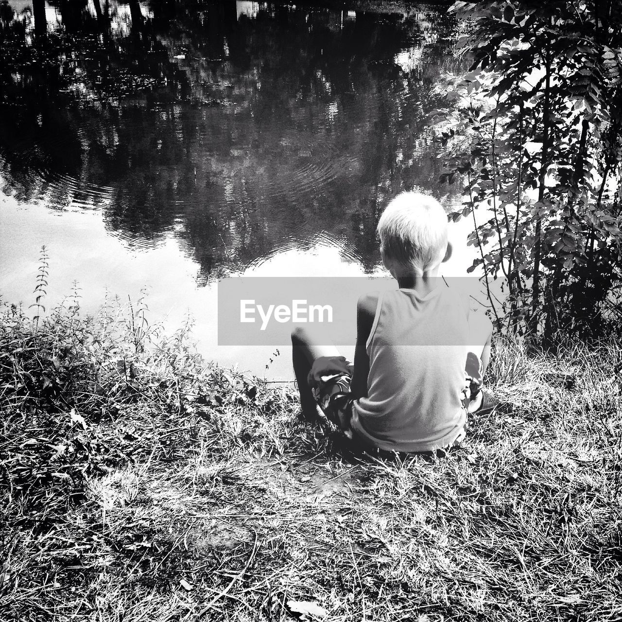 Boy sitting by lake