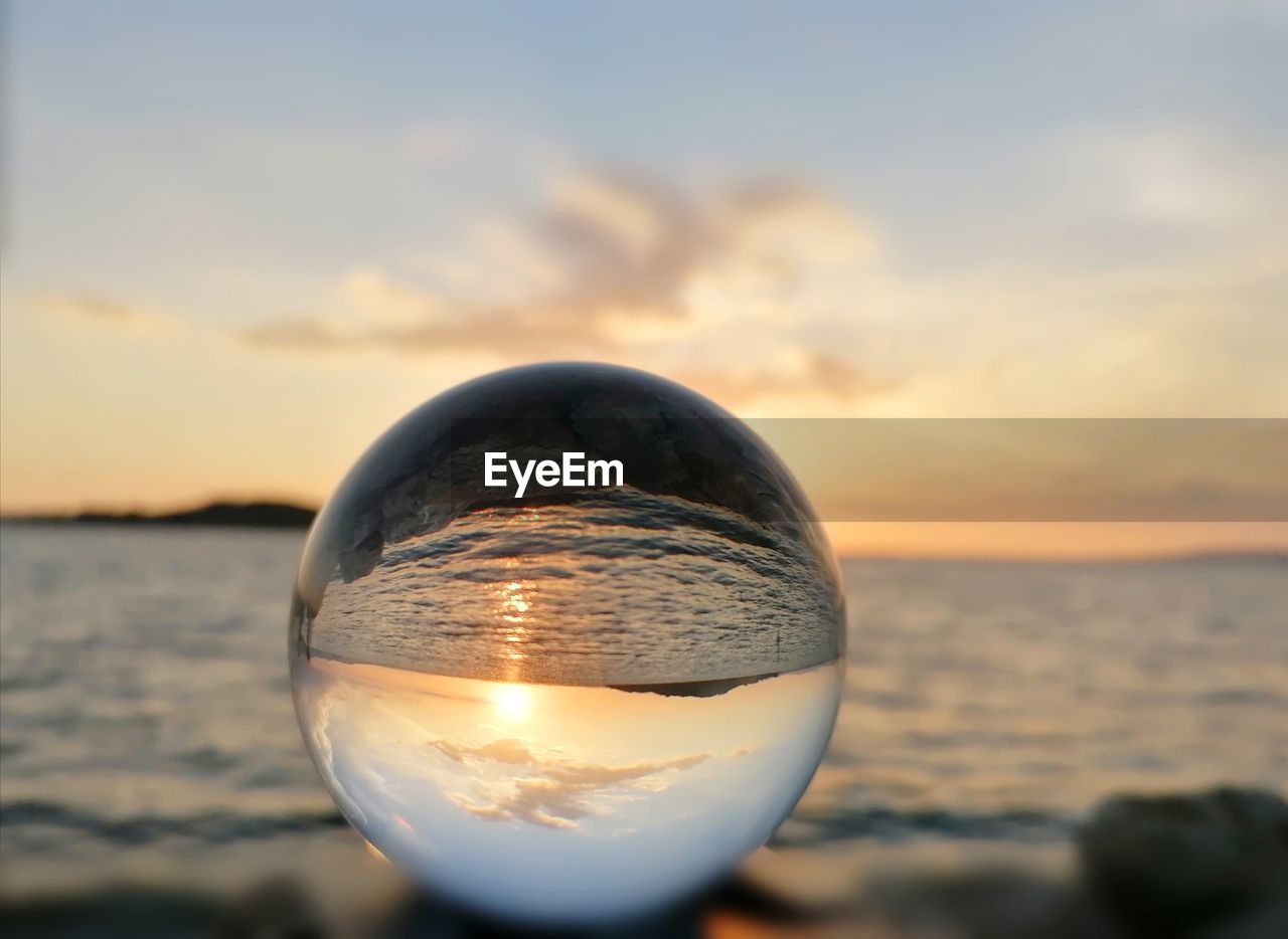 CLOSE-UP OF CRYSTAL BALL ON BEACH AGAINST SKY