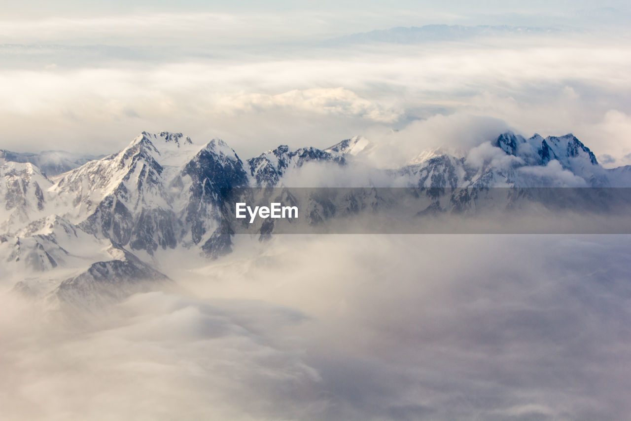 Scenic view of snow covered mountains against cloudy sky