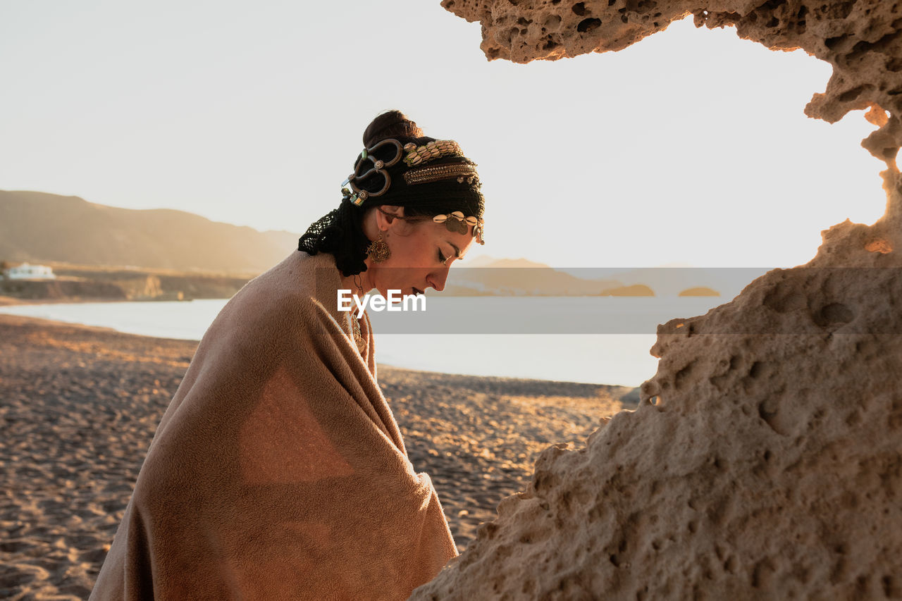 Side view of woman on beach against sky