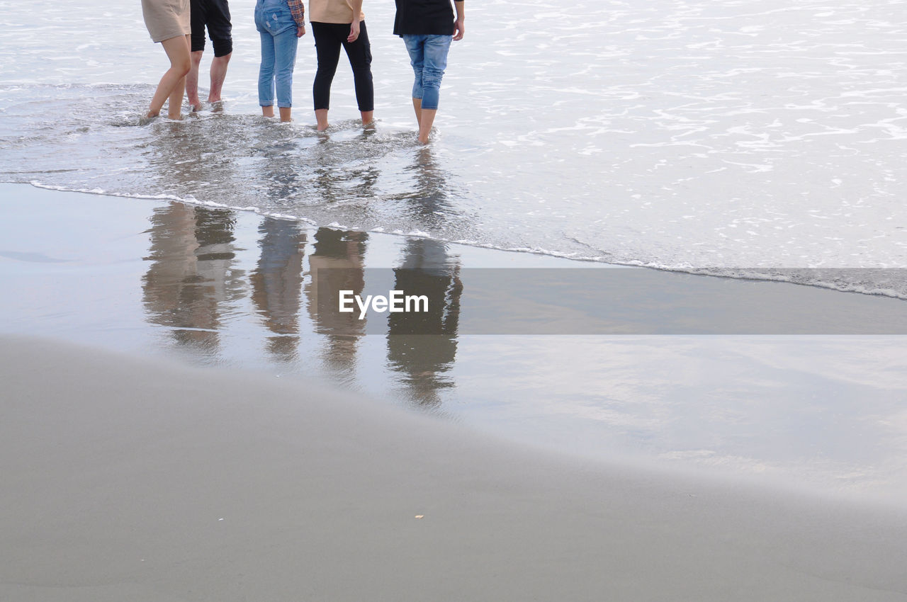 Friends standing on wet beach together.