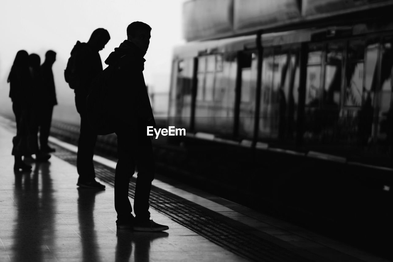 Silhouette people standing at railroad station