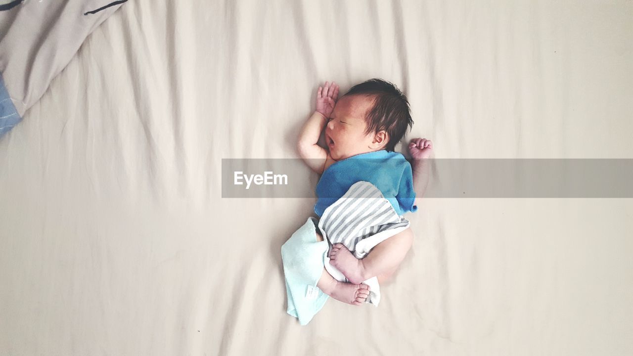 High angle view of baby girl lying on bed at home